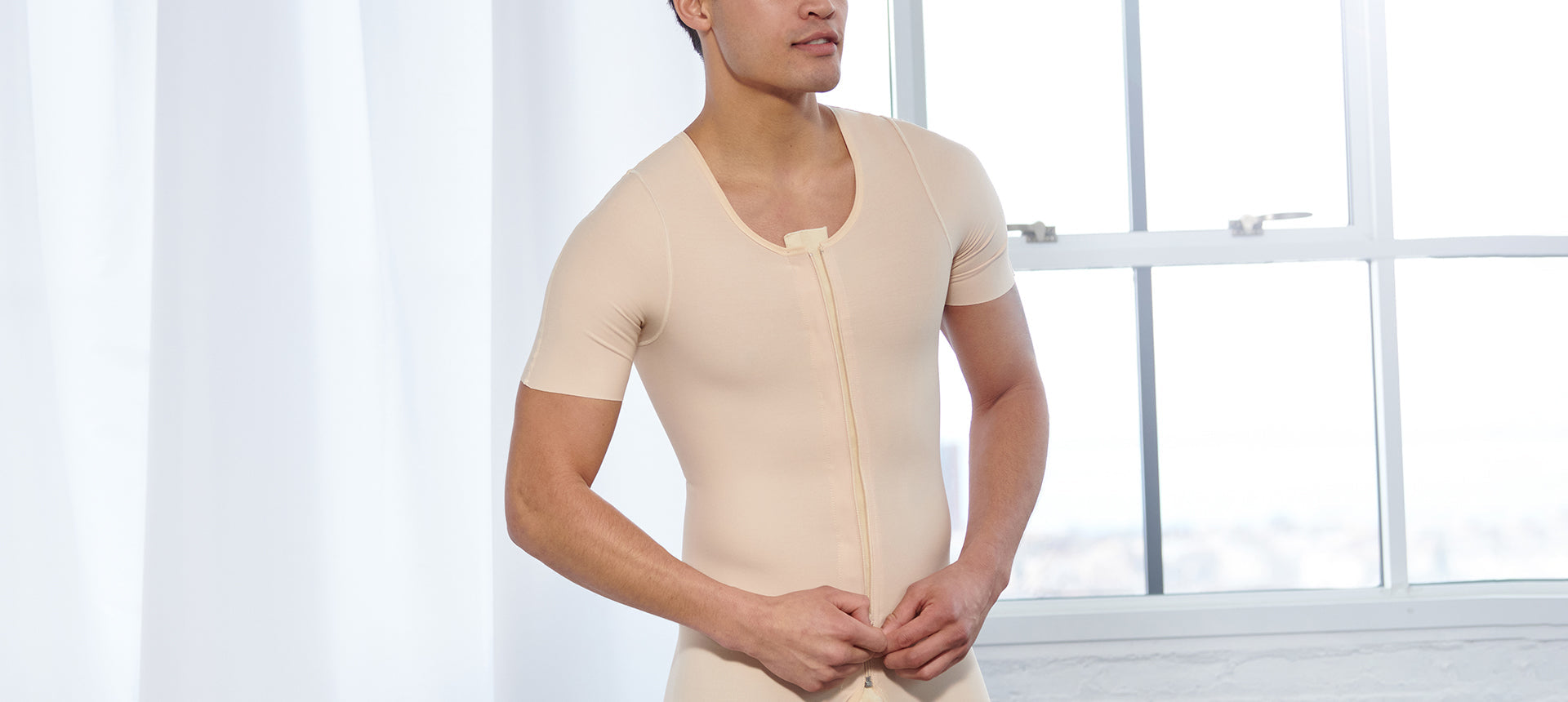 A man wearing a short-sleeve compression bodysuit for post-surgical recovery.
