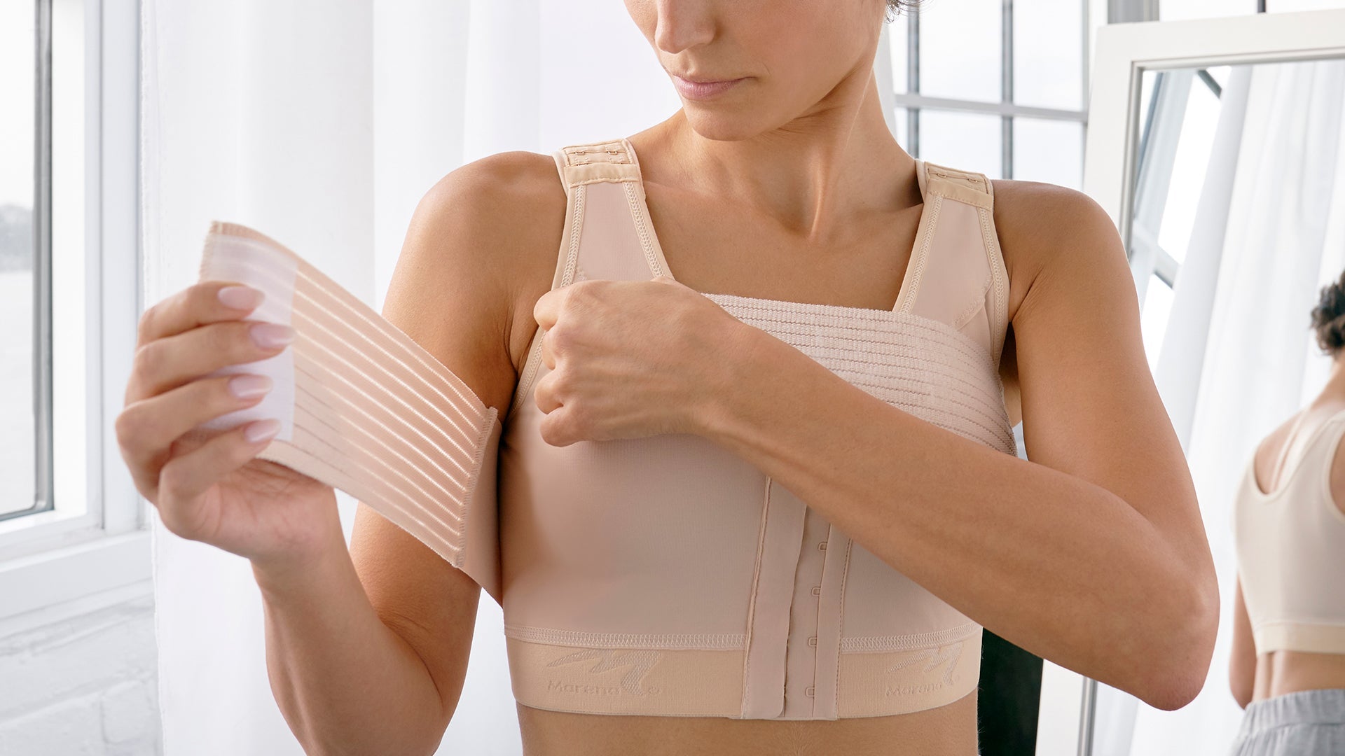 Recovery Bras - Woman secures the built-in implant stabilizer band on the B15 bra.